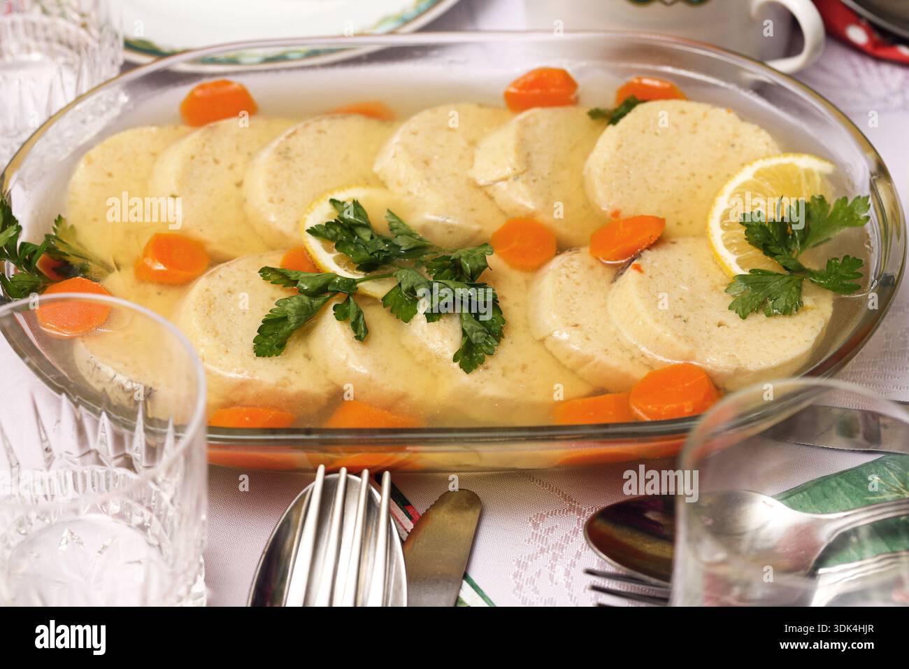 Traditioneller Fisch in Gemüsebrühe, serviert auf festlichem Tisch. Hausgemachte Feiertagsmahlzeit und klassisches europäisches Küchenkonzept im Innenbereich. Stockfoto