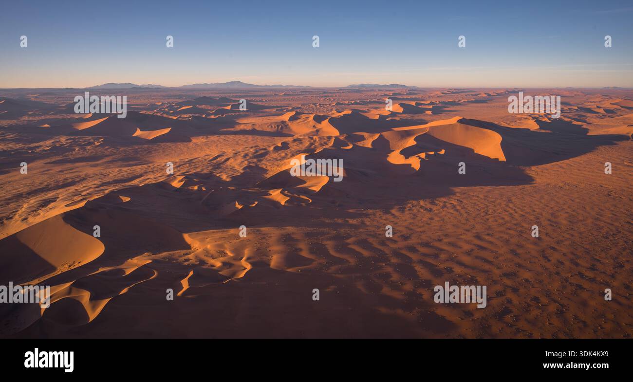Luftbild von goldenen Sanddünen in der Namib-Wüste während des Sonnenaufgangs, fotografiert aus einem Helikopter in Namibia. Stockfoto