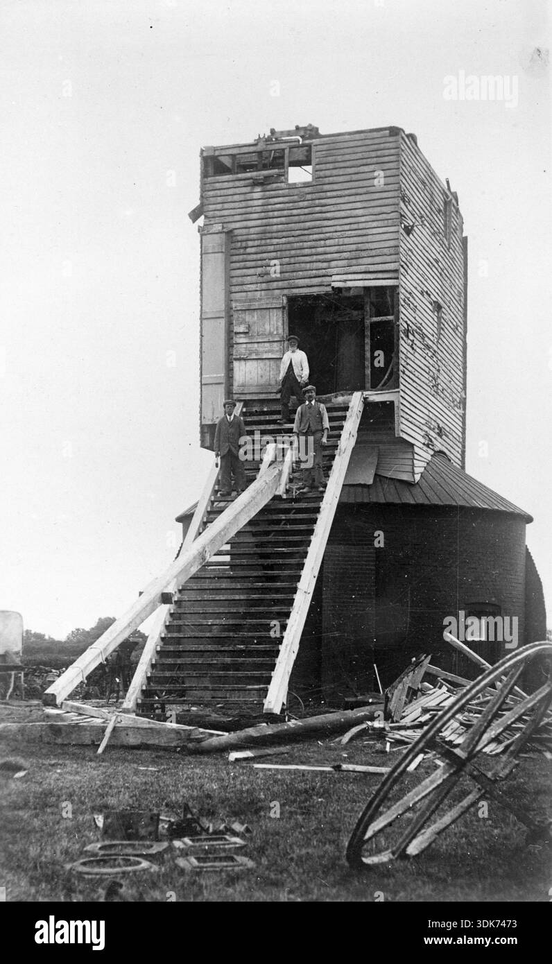 Drei Männer stehen auf den Überresten der Golden Cross Windmühle während des Abbruchs, Chalvington Road, Golden Cross, Chiddingly, Wealden, East Sussex, 1935. Im Juli 1935 wurde die Golden Cross Windmill (auch bekannt als Wickham’s Mill und Dicker Mill) demontiert, sodass nur wenige Aufzeichnungen von diesem Bild übrig blieben. Die internen Maschinen liegen verstreut auf dem Boden neben der Mühle. Die Basis der Mühle ist erhalten und wurde in ein Ferienhaus umgewandelt. Stockfoto