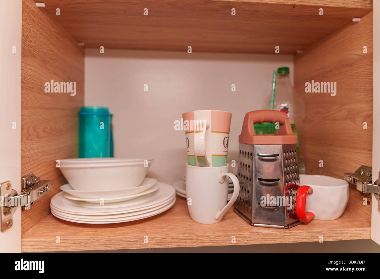 Offener Küchenschrank mit Töpfen, Tellern, Tassen und Utensilien auf Holzregalen Stockfoto