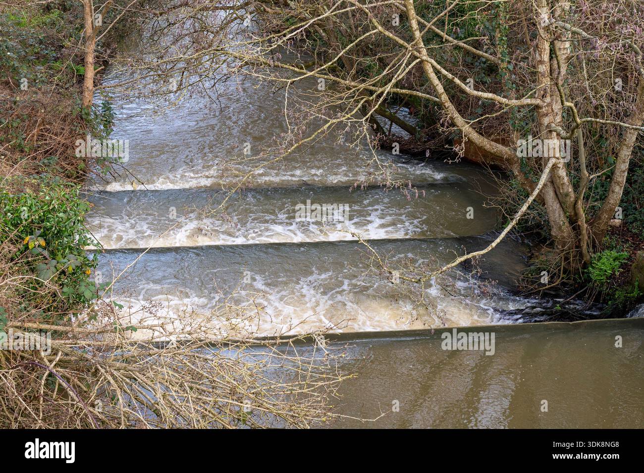 Wasserfall oder Kaskade auf einem schnell fließenden Bach oder Fluss nach starkem Regen, Fluss gefüllt mit Hochwasser, das in Kaskade oder Wasserfall stürzt. Stockfoto