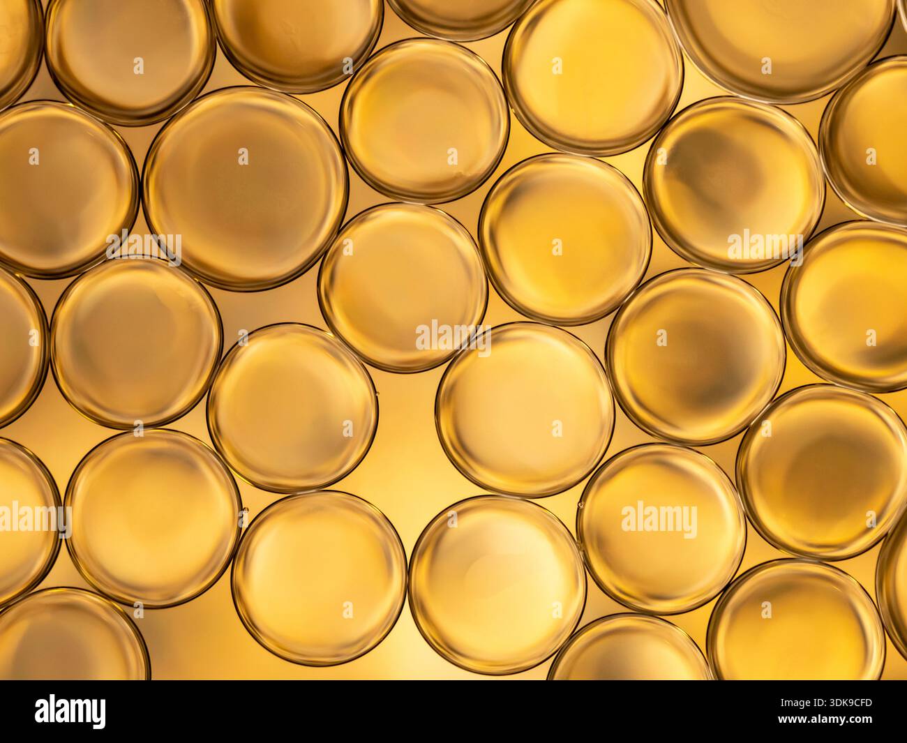 Makroaufnahme von sich überlappenden goldenen Kreisblasen, die unter warmem Licht leuchten. Glatte Oberflächen und weiche Reflexe sorgen für eine abstrakte, luxuriöse Stimmung Stockfoto