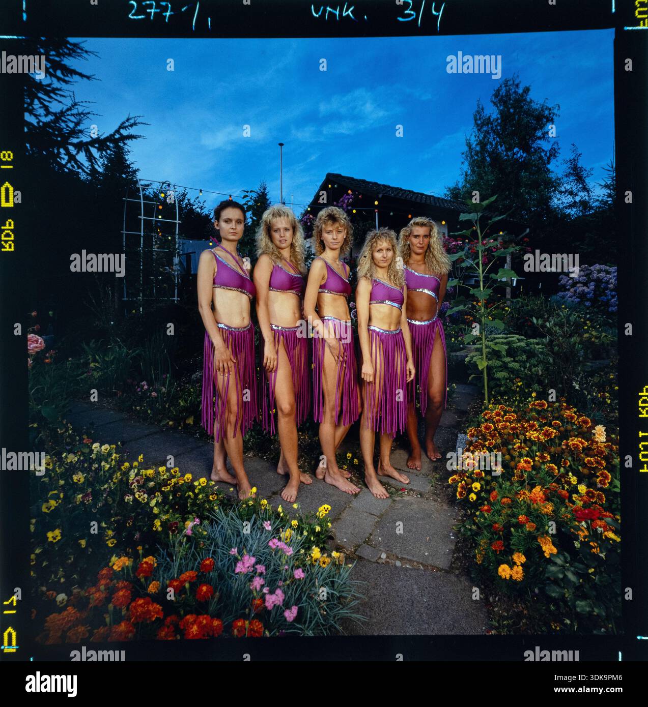 Gruppe von Tänzerinnen, die im Freien im Garten posieren, tragen dazu den purpurfarbenen 90er-Stil. Stockfoto