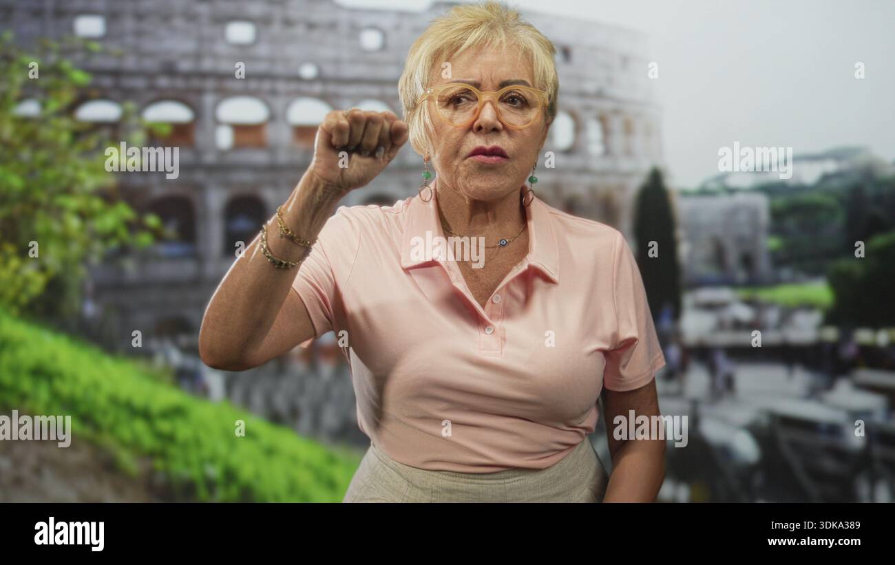 Seniorin zeigt mit den Fingern und zuckt mit den Händen vor das historische Gebäude; Verwirrungsfragen. Stockfoto