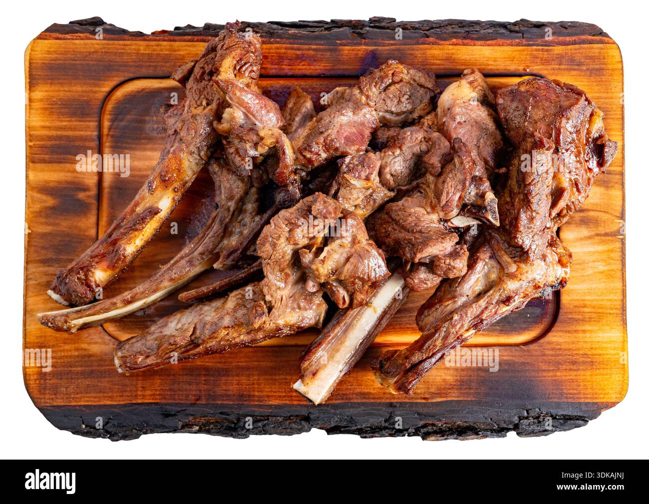 Gegrilltes Lammfleisch wird ordentlich auf einem hölzernen Schneidebrett angeordnet. Die Szene spielt tagsüber in einer Küche. Stockfoto