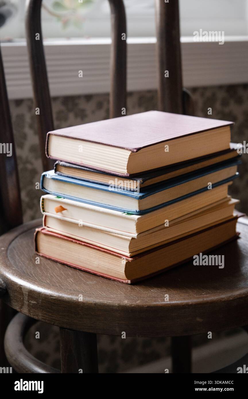 Stapel alter Bücher auf einem Holzstuhl Stockfoto