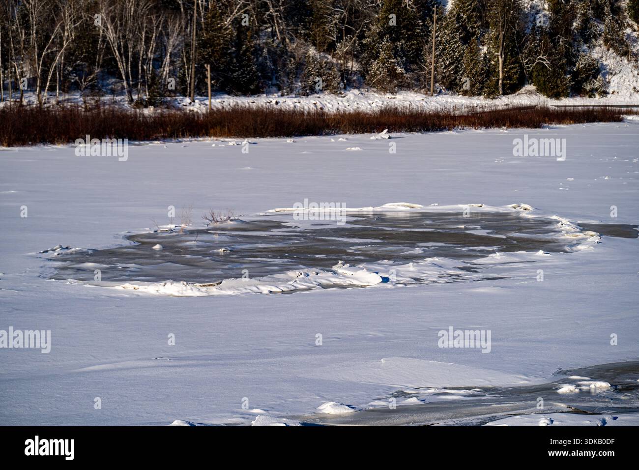 Blick auf gefrorene Flussoberfläche mit offenem Wasser. Stockfoto