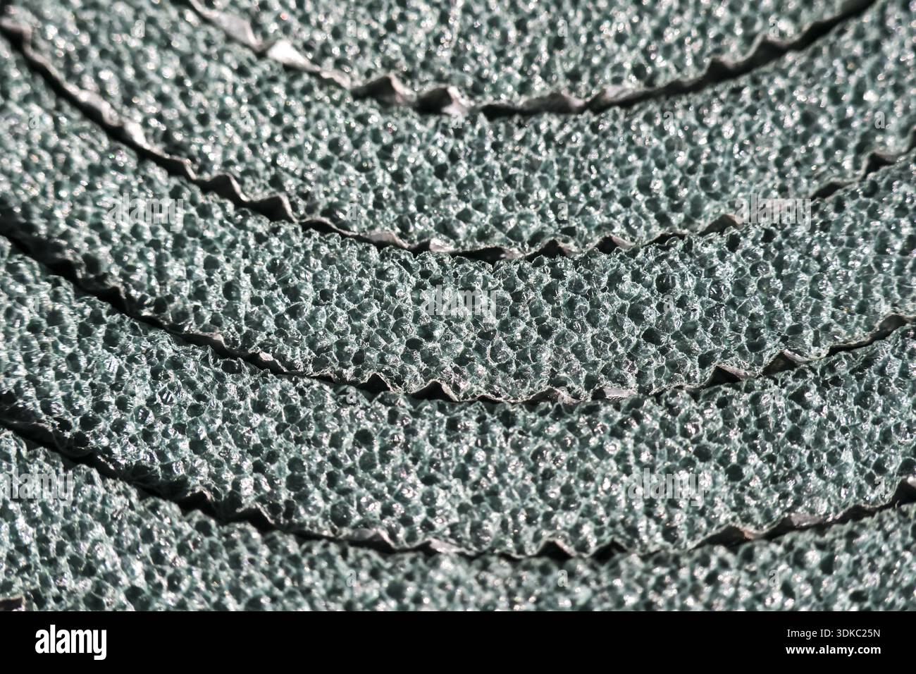 Makrodetail der grünen Schlafkissen-Schaumtextur. Ein abstrakter Hintergrund von gerollten Campinggeräten und -Ausrüstungen, der poröse, holprige Oberflächenmaterialien f zeigt Stockfoto