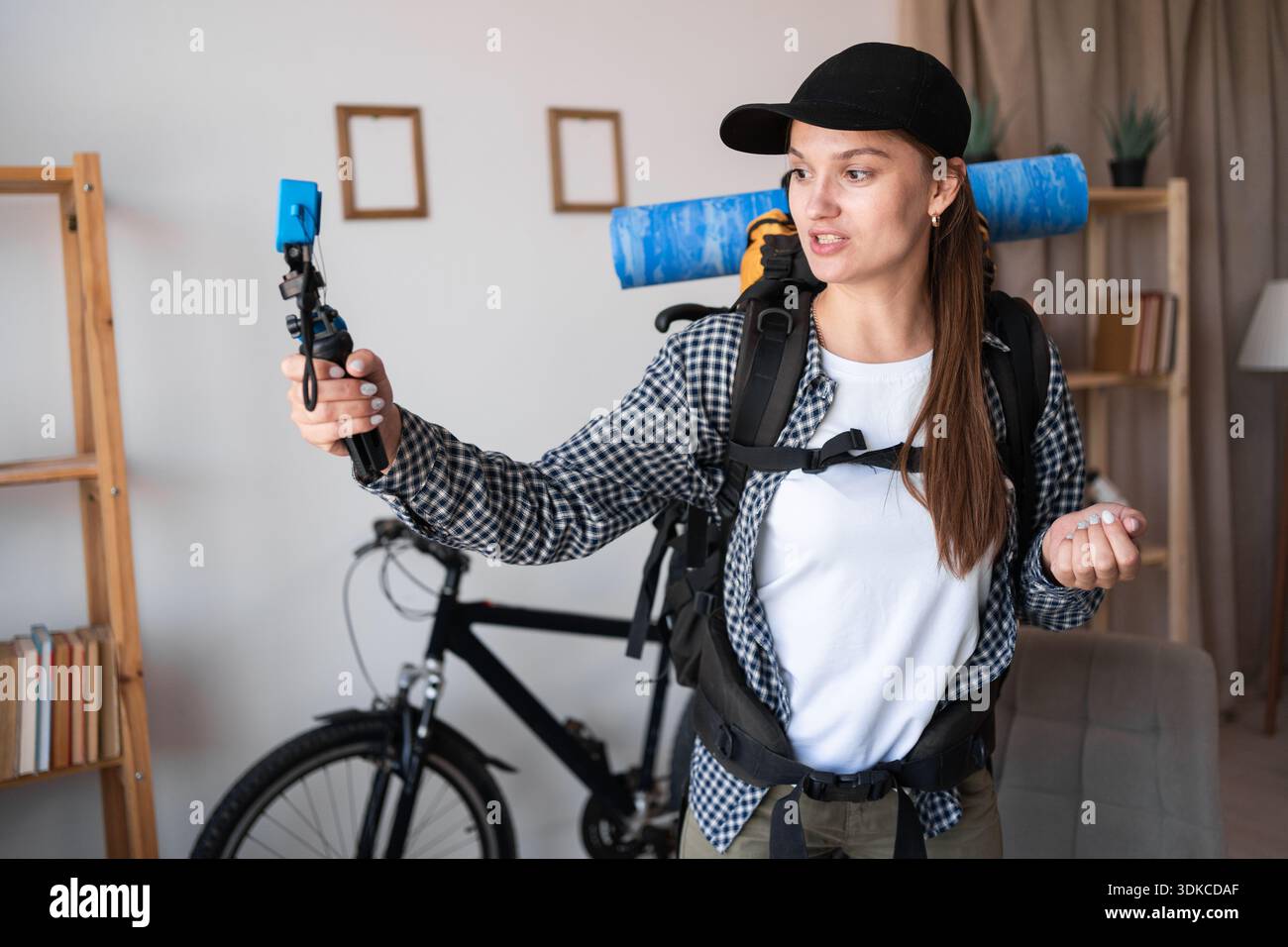 Wandern, Reisen, Erholung und Ausflugskonzept. Junge Reisende Frau, die einen Rucksack hält, um eine Wanderung zu machen und Videos mit 4K-Kamera im Wohnzimmer aufzunehmen. Fem Stockfoto