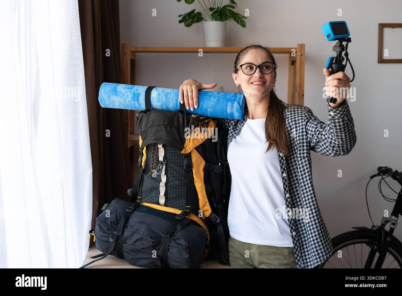 Wandern, Reisen, Erholung und Ausflugskonzept. Junge Reisende Frau, die einen Rucksack hält, um eine Wanderung zu machen und Videos mit 4K-Kamera im Wohnzimmer aufzunehmen. Fem Stockfoto