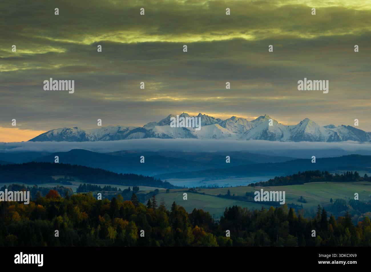 Panoramablick auf das schneebedeckte Tatra-Gebirge bei Sonnenuntergang mit dramatischen Wolken und überlagerten Hügeln im Vordergrund in Südpolen. Stockfoto