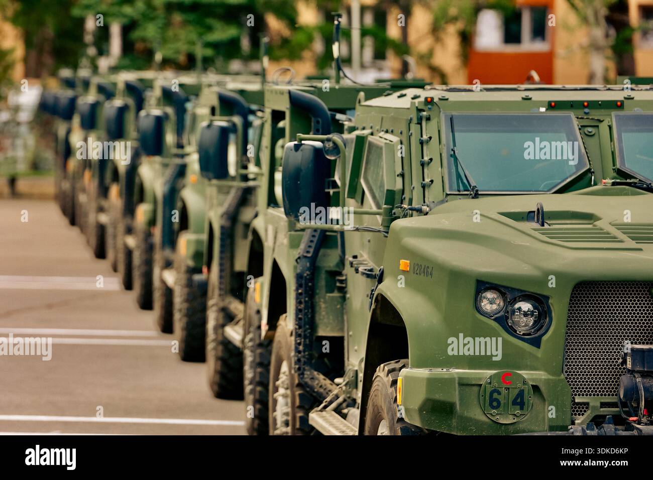 Reihe grüner militärischer Einsatzfahrzeuge, die in Formation auf einer Militäreinrichtung geparkt sind Stockfoto