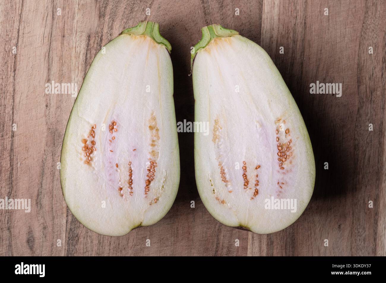 Das Innere einer in der Hälfte geschnittenen Aubergine auf einem Holzschneidebrett Stockfoto