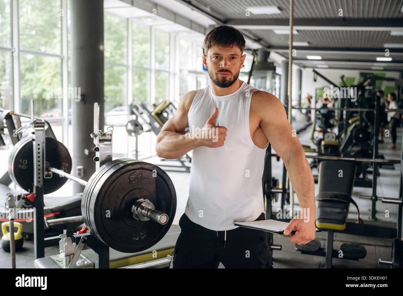 Der Besitzer des Fitnessstudios hält den Notizblock. Ein starker Mann steht. Stockfoto