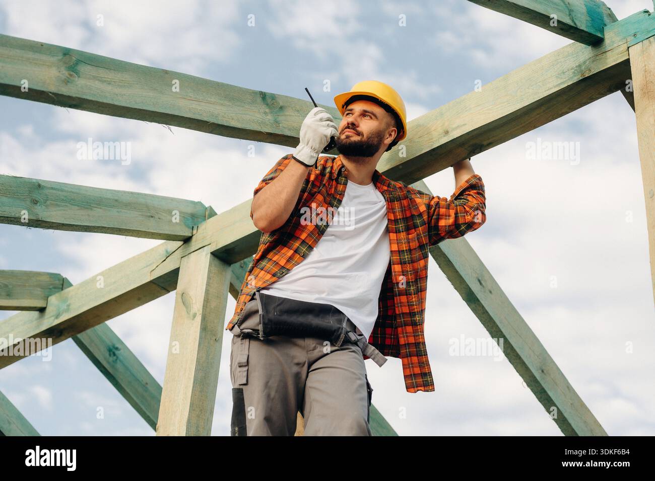 Befehle über Walkie-Talkie erteilen. Bauarbeiter ist auf dem Dach eines Hauses. Stockfoto