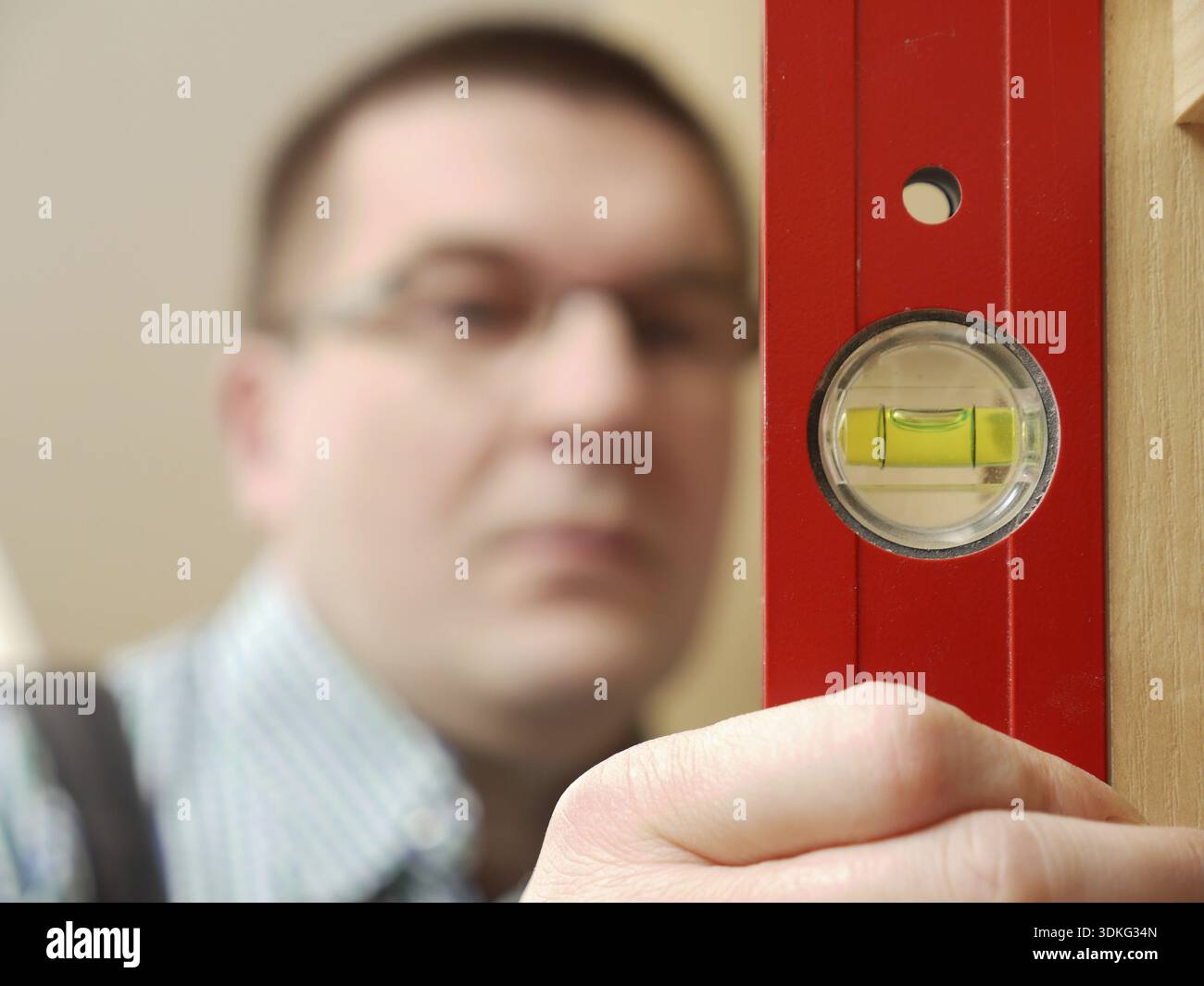 Nahaufnahme des Zimmermanns, der auf die Wasserwaage schaut Überprüfen Sie die vertikale Positionierung der Möbel - geringe Schärfentiefe Stockfoto