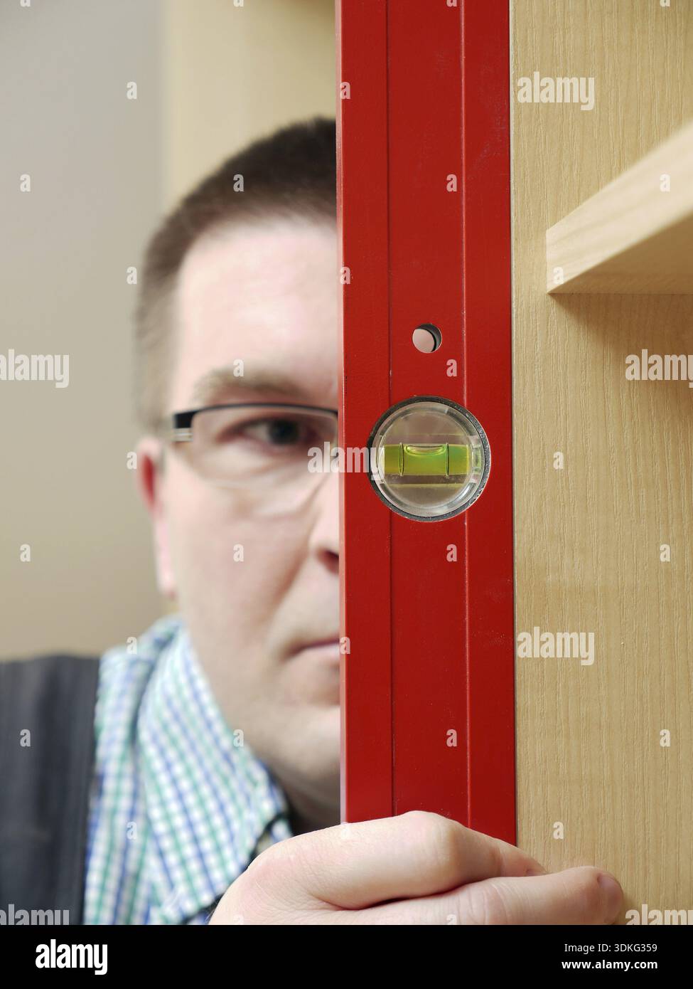 Nahaufnahme des Zimmermanns, der auf die Wasserwaage schaut Überprüfen Sie die vertikale Positionierung der Möbel - geringe Schärfentiefe Stockfoto