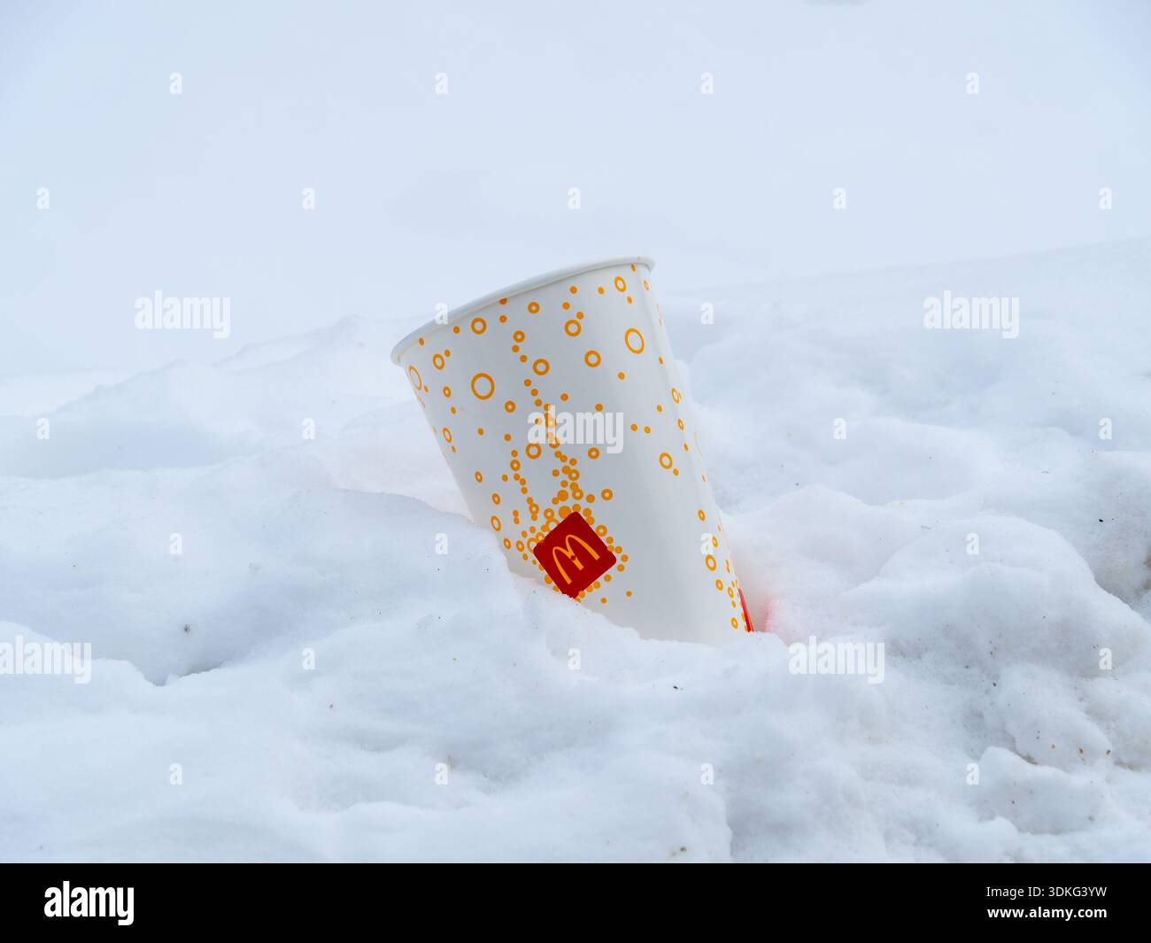 McDonald's Pappbecher im Schnee mit einem verspielten, minimalistischen Design aus orangefarbenen und gelben Kreisen, die Fizz oder Blasen darstellen Stockfoto