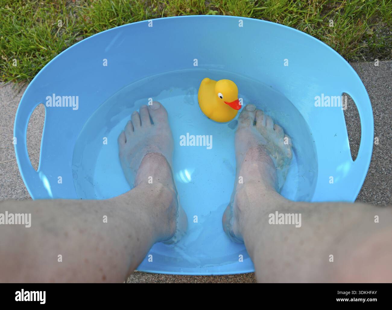 Kühlung, Wärme, Hitzewelle, Kühlung, Füße, Fuß, Wasser, kalt, Abkühlen, Wanne, bunt, blau, gelb, Fußbad, Ente, Plastikente, quietschende Ente, Müll Stockfoto