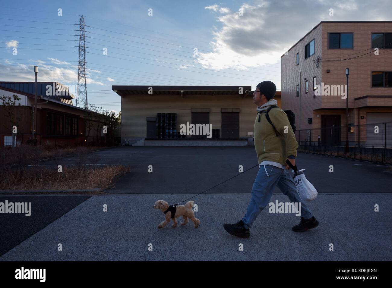 Ein japanischer Mann, der mit einem kleinen Hund vor dem Gebäude in Kanagawa, Japan, herumläuft. Stockfoto