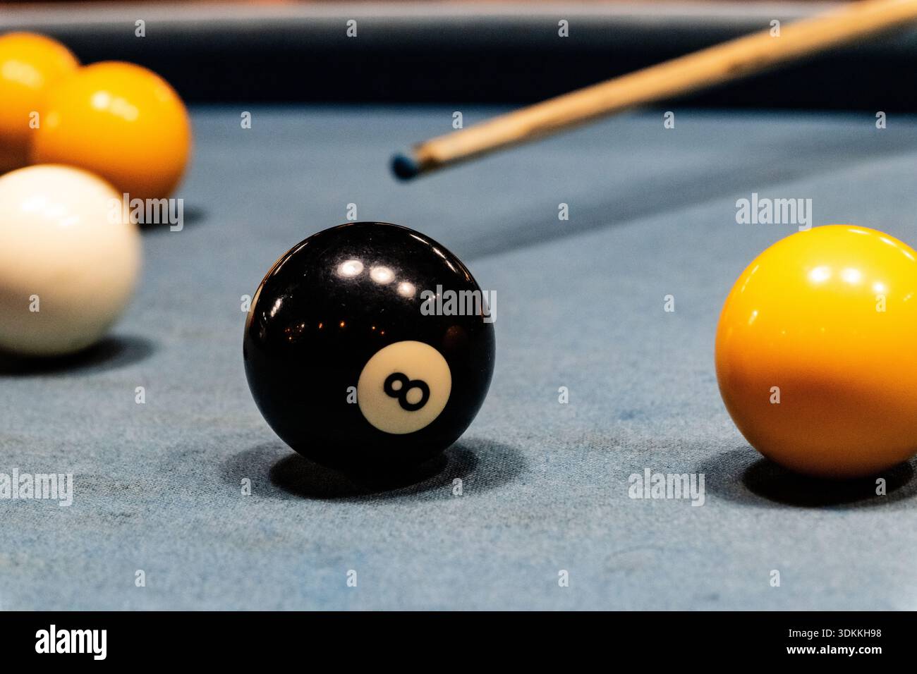 Englisches Billardspiel mit dem Acht schwarzen Ball und dem Queue dahinter, der auf den Queue Ball zielt Stockfoto