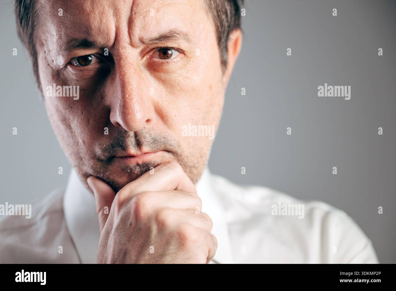 Seriöser Geschäftsmann Hand am Kinn tief in Gedanken Nahaufnahme Porträt, selektiver Fokus Stockfoto