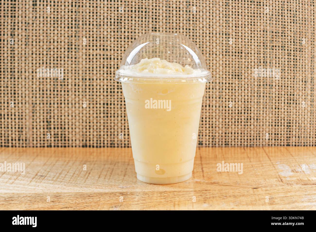 Ein Glaskrug, der bis zum Rand mit blassgelber Limonade gefüllt ist, wo dünne Zitrusscheiben und frische Minze zwischen dem Eis schweben, das in der Sonne glitzert. Stockfoto