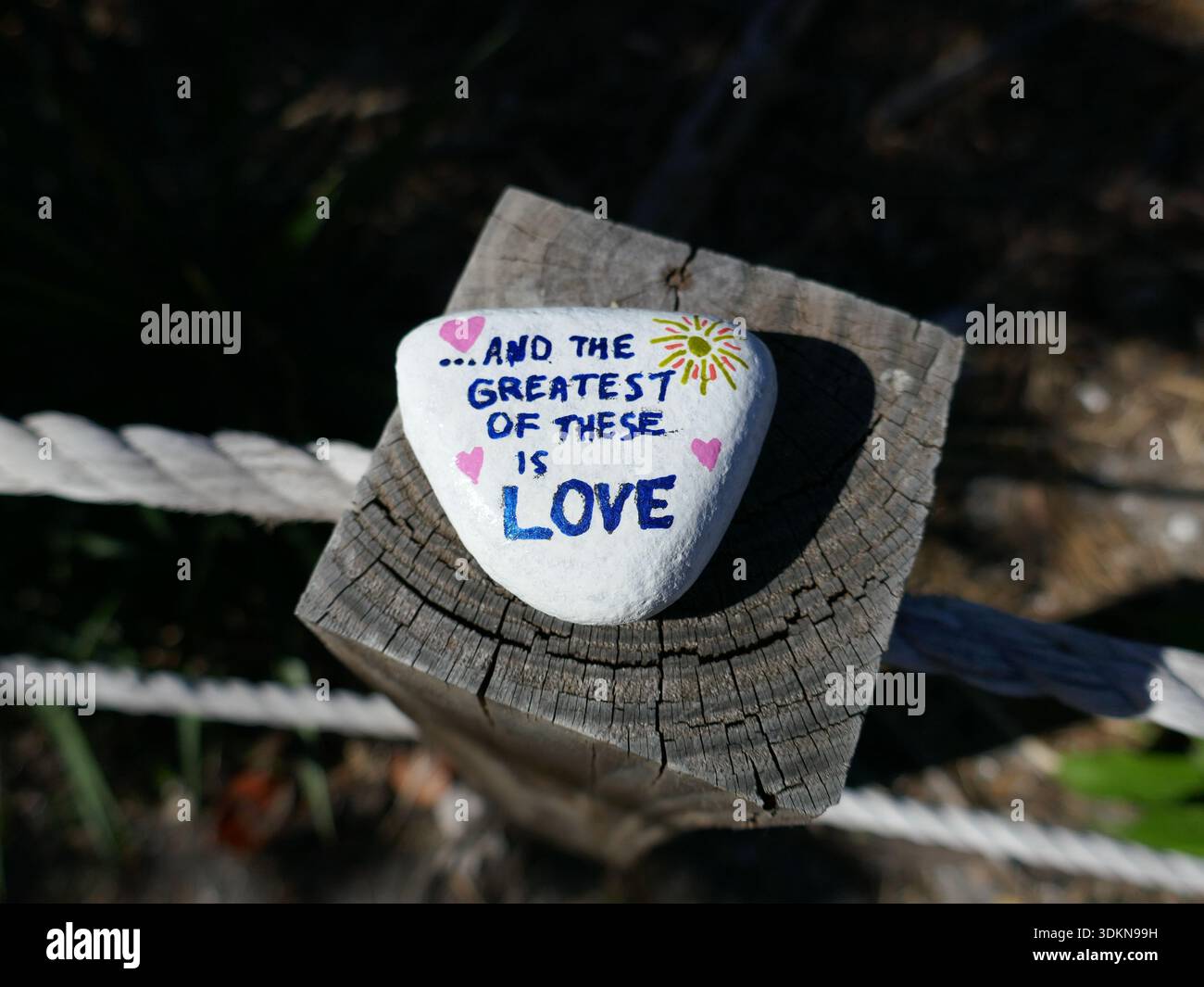 Oben auf einem Holzpfosten mit und das größte davon ist Liebe gemalt auf Freundlichkeit Felsen Stockfoto