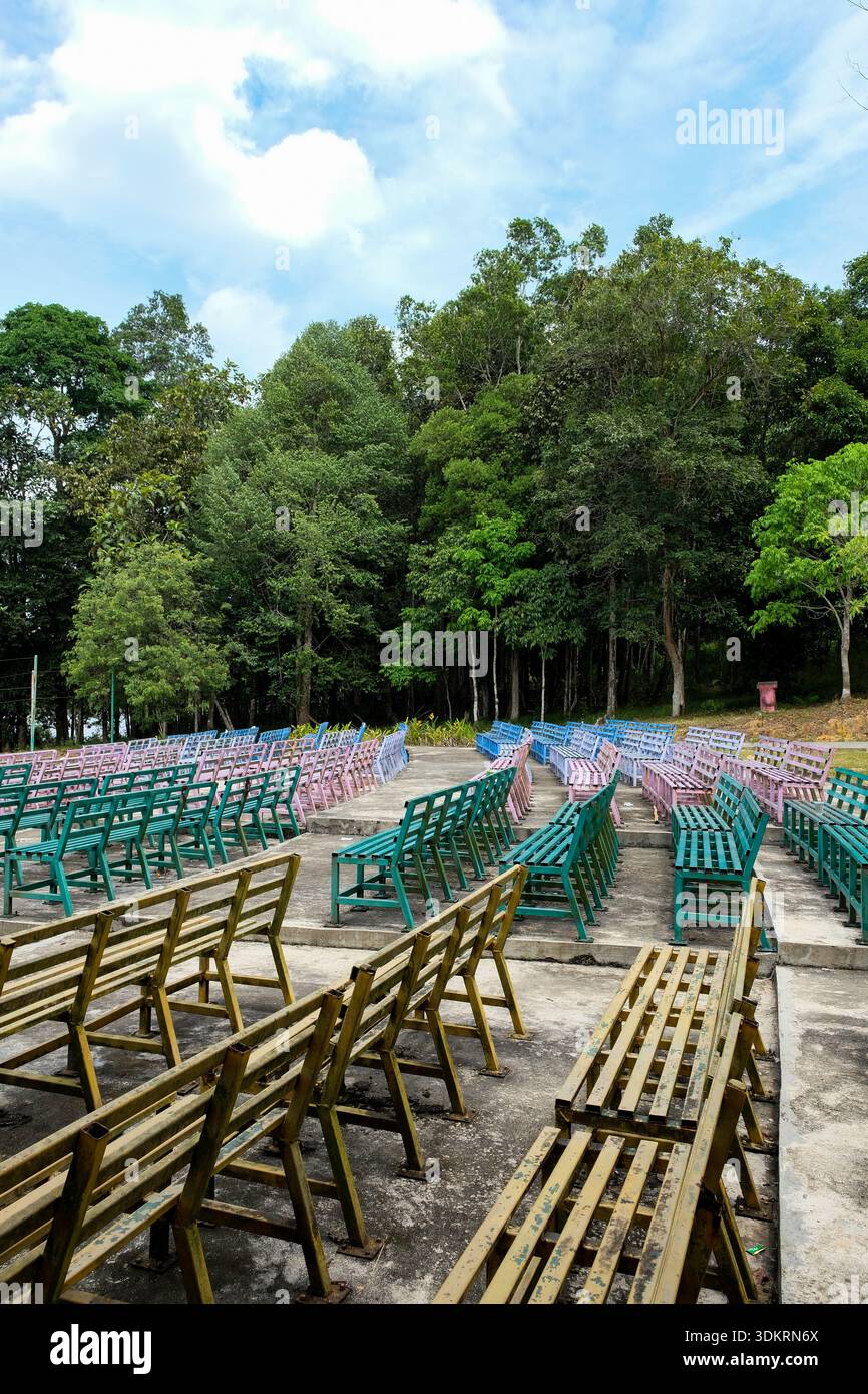 Perspektivischer Blick auf sauber ausgerichtete bunte Metallbänke in einem öffentlichen Park Stockfoto