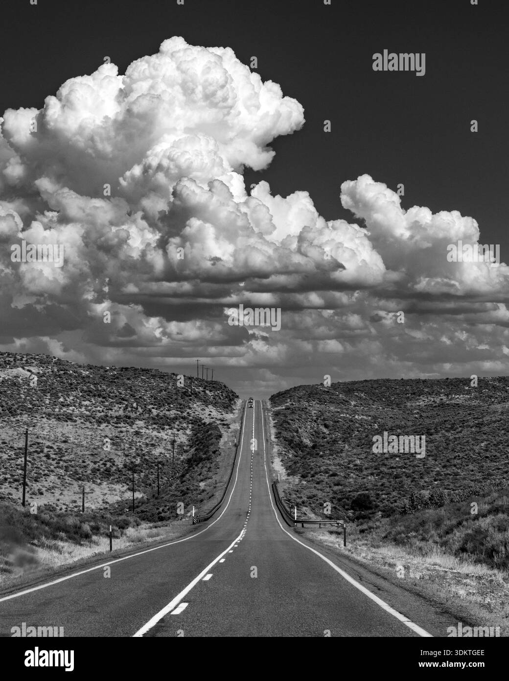 USA, Idaho, Fairfield, Cumulus Wolken über leeren Straßen, die Landschaft kreuzen, schwarz-weiß Stockfoto