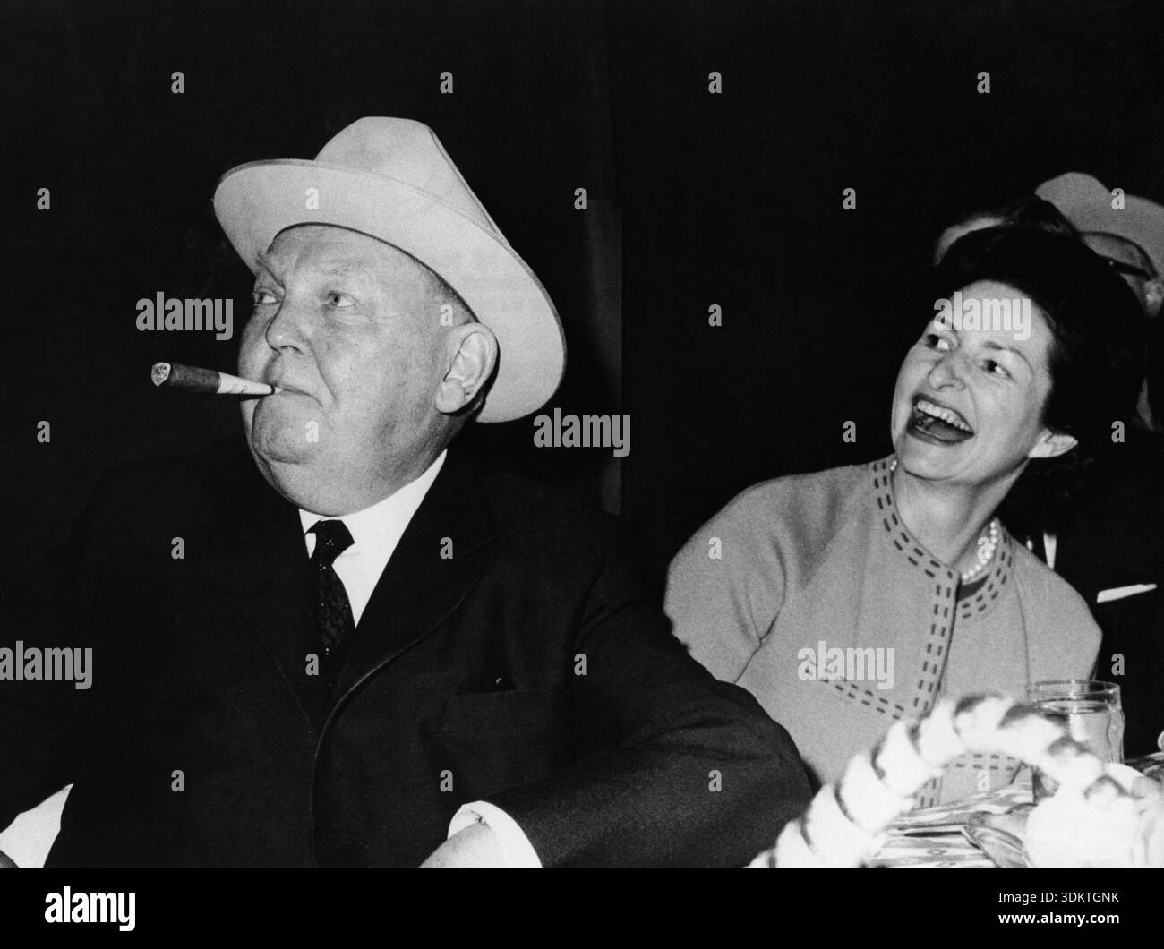 Bundeskanzler Ludwig Erhard und Lady Bird Johnson, Ehefrau von Lyndon B. Johnson, beobachten, wie der US-Präsident während Erhards Besuch auf der LBJ Ranch in der Nähe von Stonewall und Johnson City in Texas weitere Cowboyhüte an die deutsche Delegation verteilt. [Automatisierte Übersetzung] Stockfoto