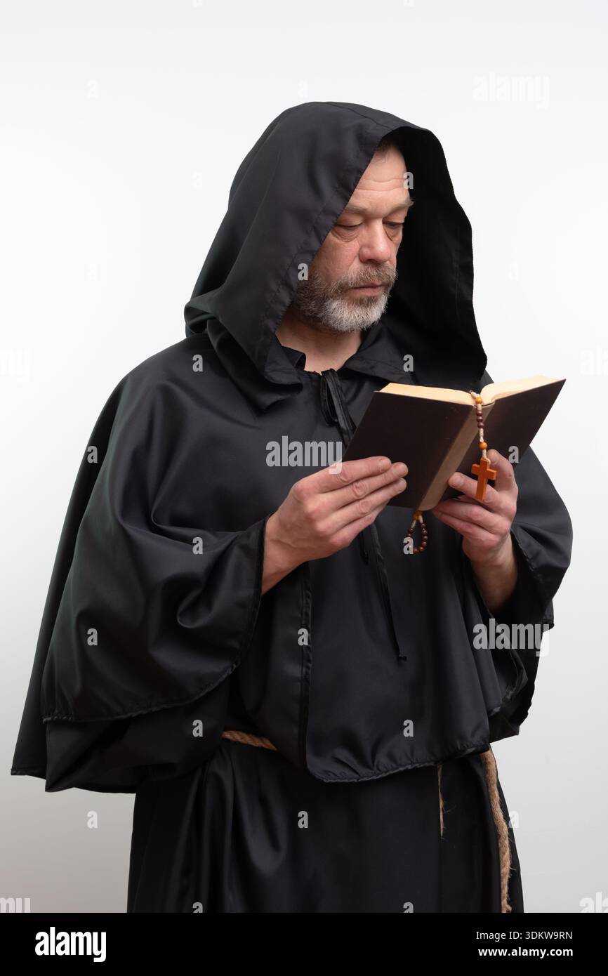 Männlicher Mönch liest offenes Buch mit Rosenkranz, isoliert Stockfoto