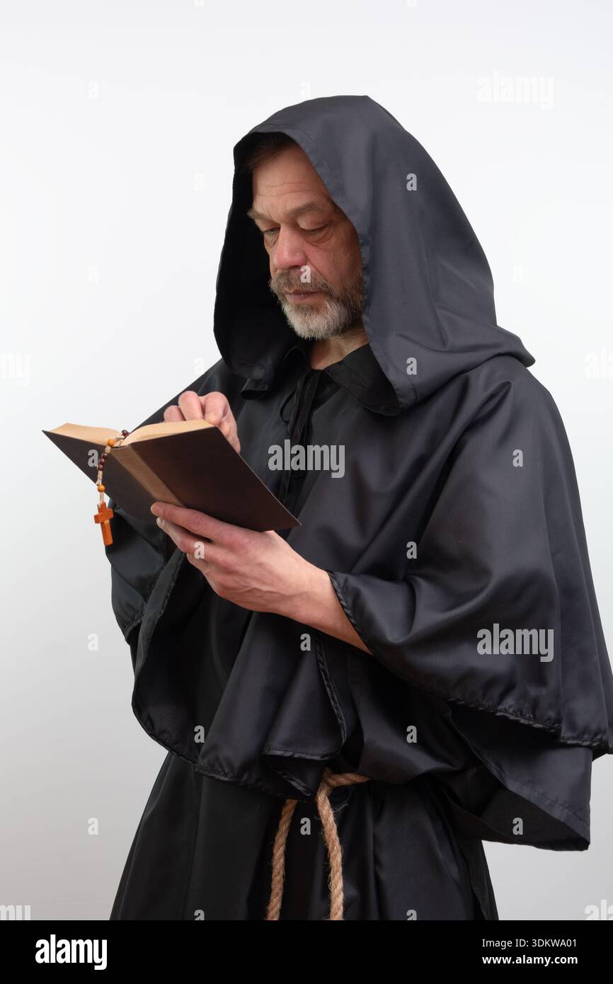 Bärtiger Mönch mit Kapuze, der religiöses Buch im Studio umschlägt Stockfoto