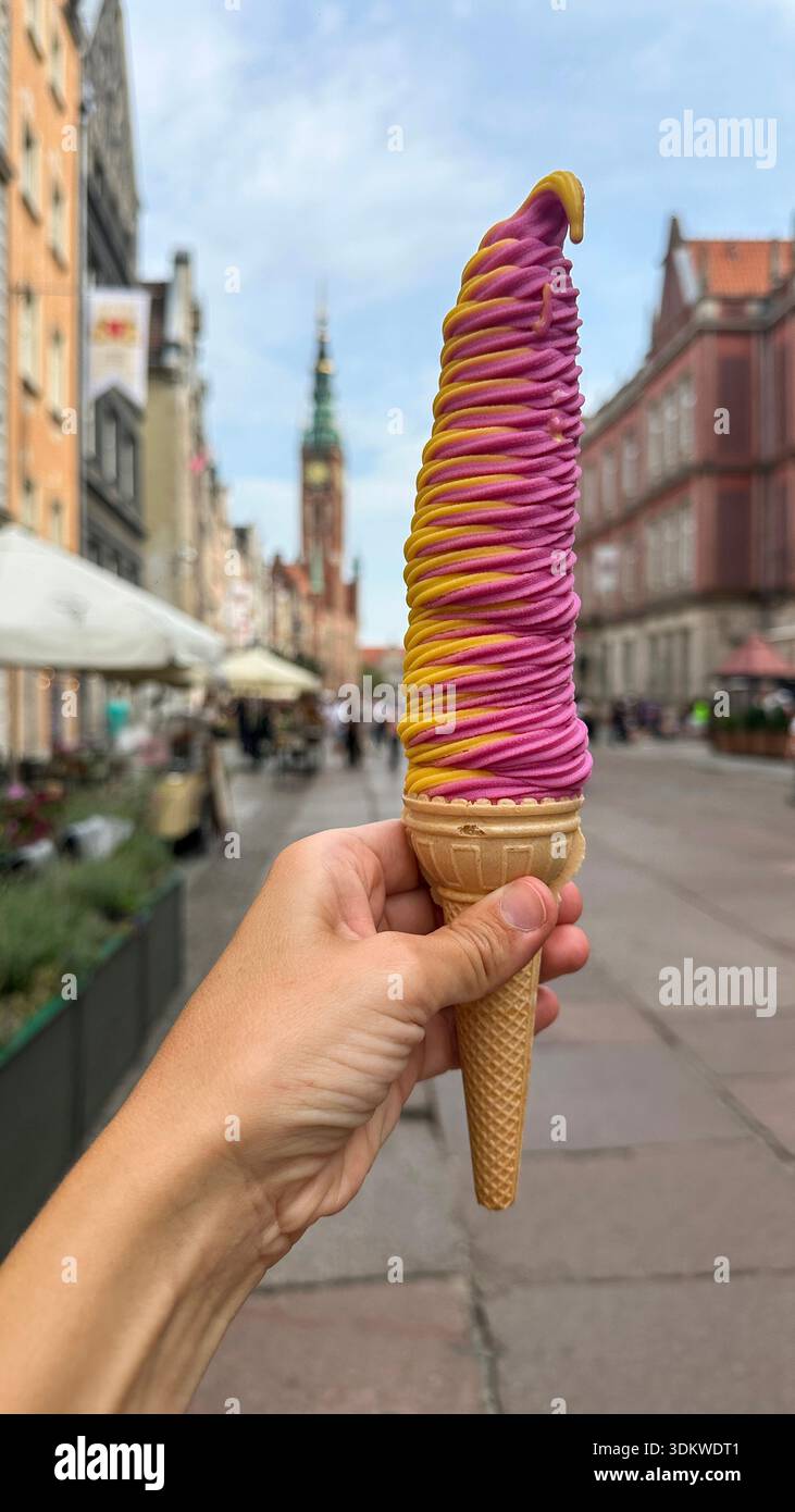 Hand hält bunte, weiche Eiskegel auf der europäischen Altstadt - Smartphone-aufgenommenes Stockfoto