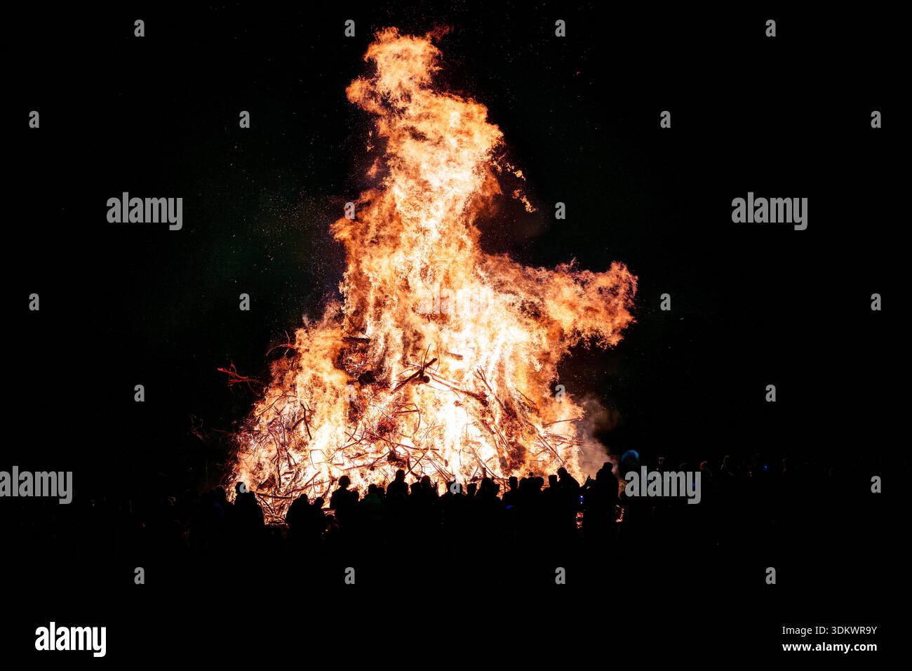 Intensive Flammen und aufsteigende Funken bei einem großen öffentlichen Brand. Eine abstrakte Darstellung von Energie, Transformation und Urverbindung. Stockfoto