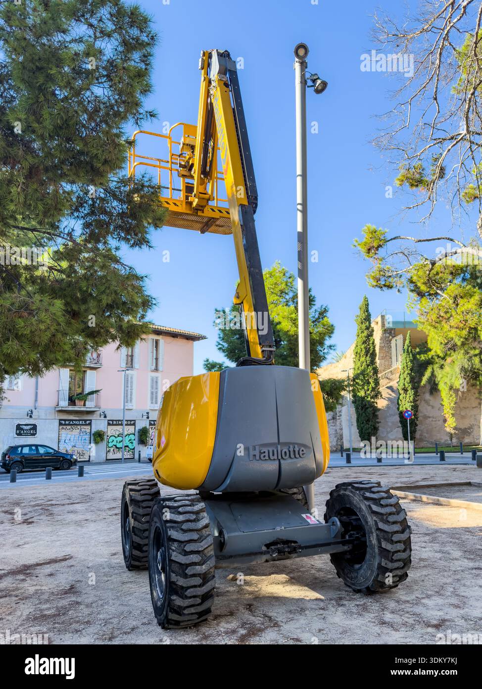 Ein Bauaufzug, der auf einer Baustelle positioniert ist und bereit ist, Arbeiter für Wartungs- oder Bauaufgaben in einem städtischen Gebiet zu heben - Smartphone-aufgenommenes Stockfoto
