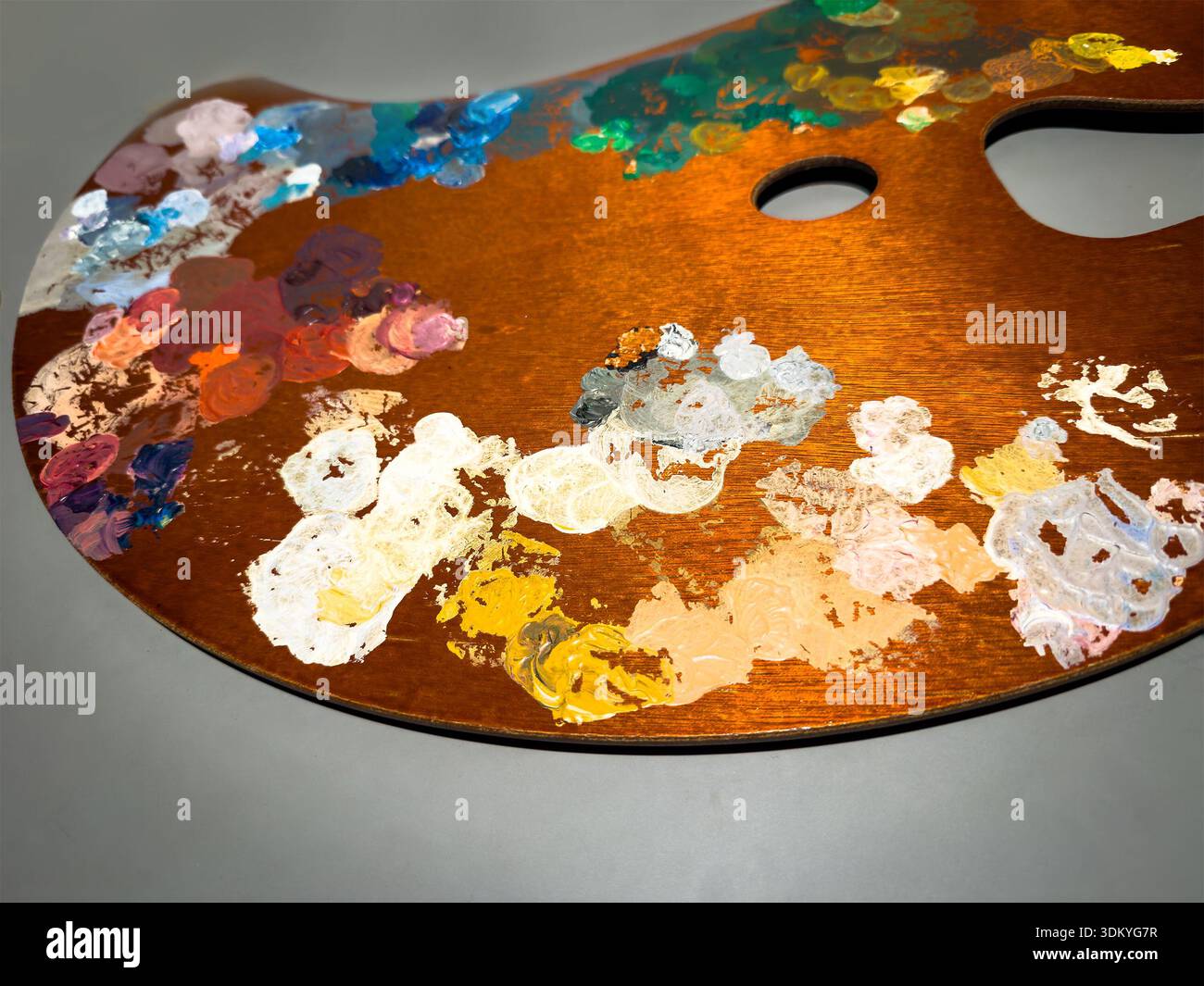 Die Holzpalette eines Künstlers bietet lebendige Farben und gemischte Öl- oder Acrylfarben, die die Essenz von Kreativität und Kunstfertigkeit einfangen - Smartphone-aufgenommenes Stockfoto