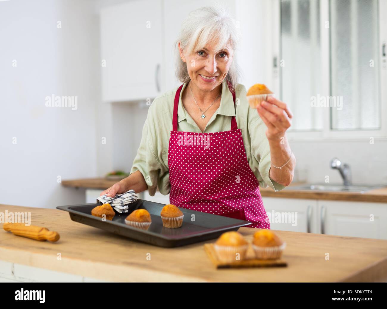 Reife Frau, die zu Hause VanilleMuffins backt Stockfoto