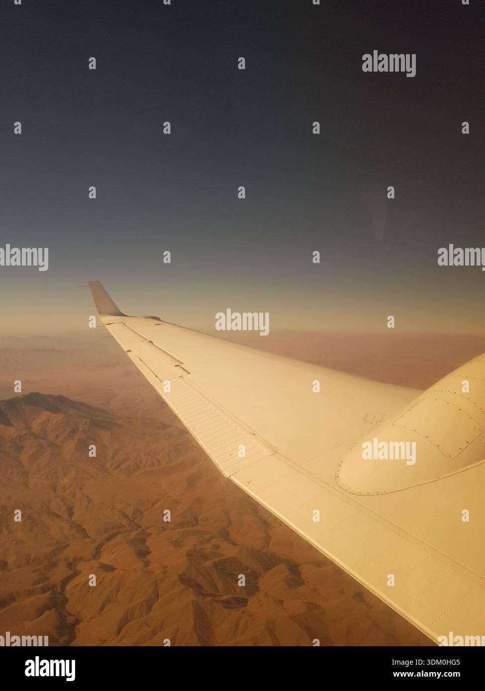 Dramatische Luftaufnahme von einem Passagierfenster um 07:55 UHR am 11. September 2018, kurz nach dem Start vom Kabul International Airport. Das Bild zeigt einen großen Flugzeugflügel über dem zerklüfteten, sonnendurchfluteten Hindukusch in Afghanistan. Stockfoto