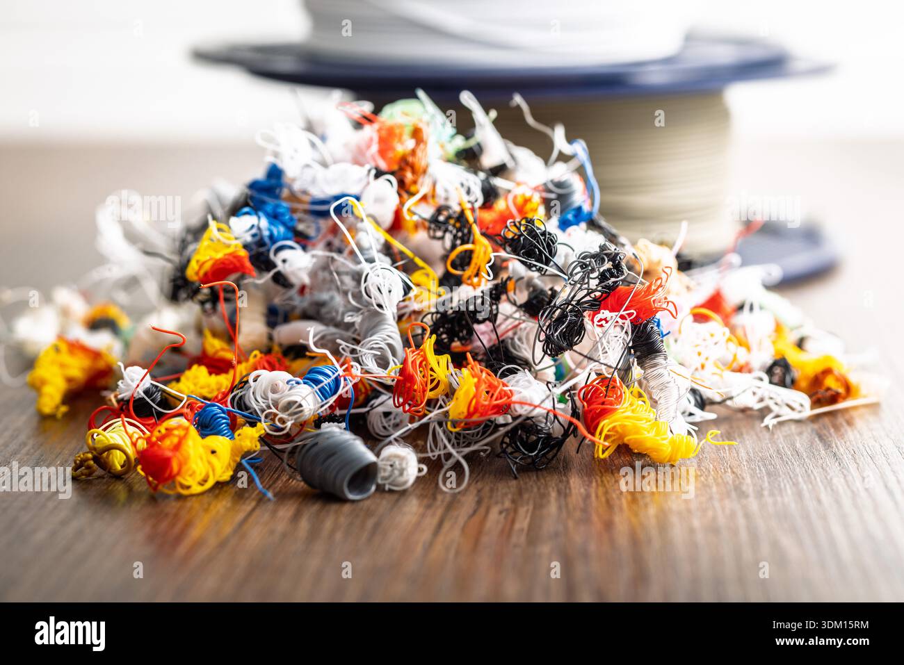 Abfall des 3D-Druckers. Plastikfäden kacken auf einen Holztisch. Stockfoto