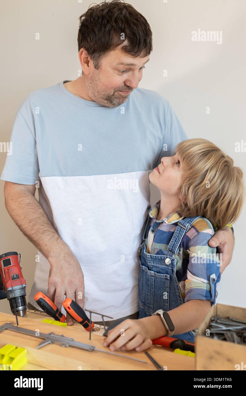 Der Vater lehrt seinem Kind den Umgang mit Werkzeugen und hilft ihm. Die Konzepte von Familie und Einheit, ein gemeinsames Hobby, der Stolz der Vaterschaft und der Passin Stockfoto
