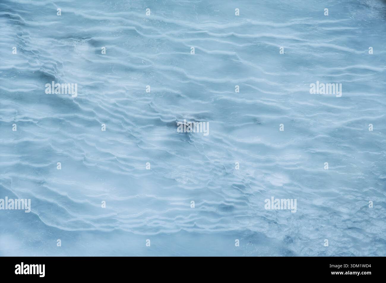 Unter dem sanften Winterlicht reflektiert die glatte Eisoberfläche atemberaubende Muster und lädt in einer kühlen Atmosphäre zu Ruhe und Gelassenheit ein. Stockfoto