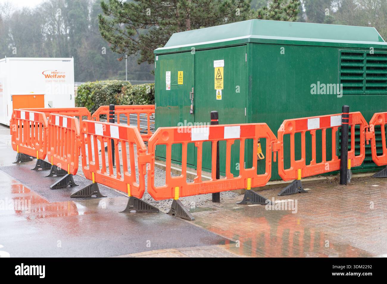 Stromversorgung des grünen Sreel-Schranks in einem Einzelhandelspark. Der belüftete Stahlcontainer hat Barrieren von Werkern um die Einheit herum. Stockfoto