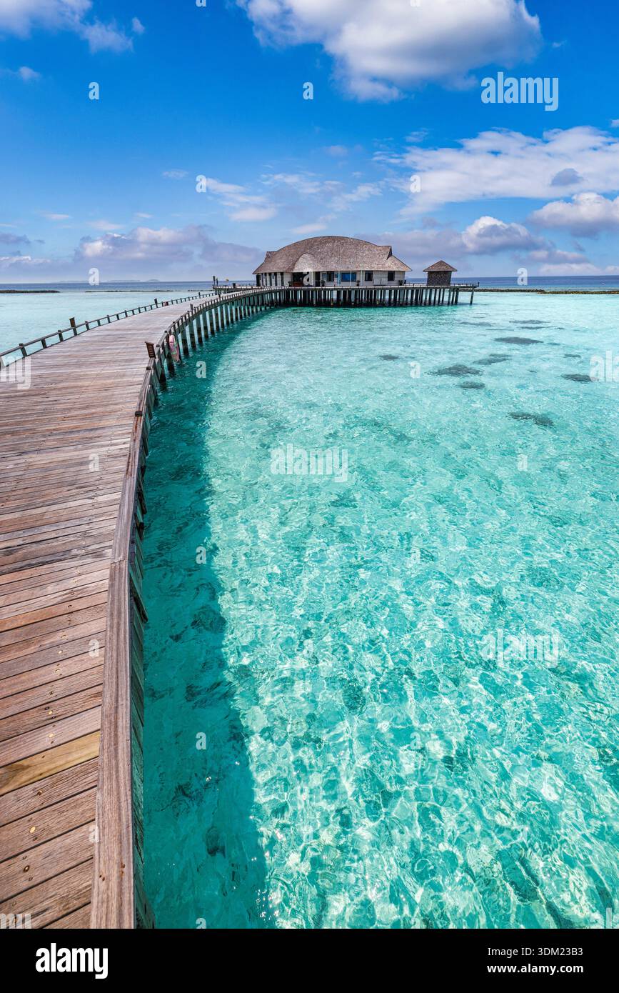 Malediven gekrümmter Pier über Wasser Villen blauer Himmel atemberaubendes türkisfarbenes ruhiges Meer ruhige Meereslandschaft tropisches Paradies Luxus Resort Reiseziel sonnig Stockfoto