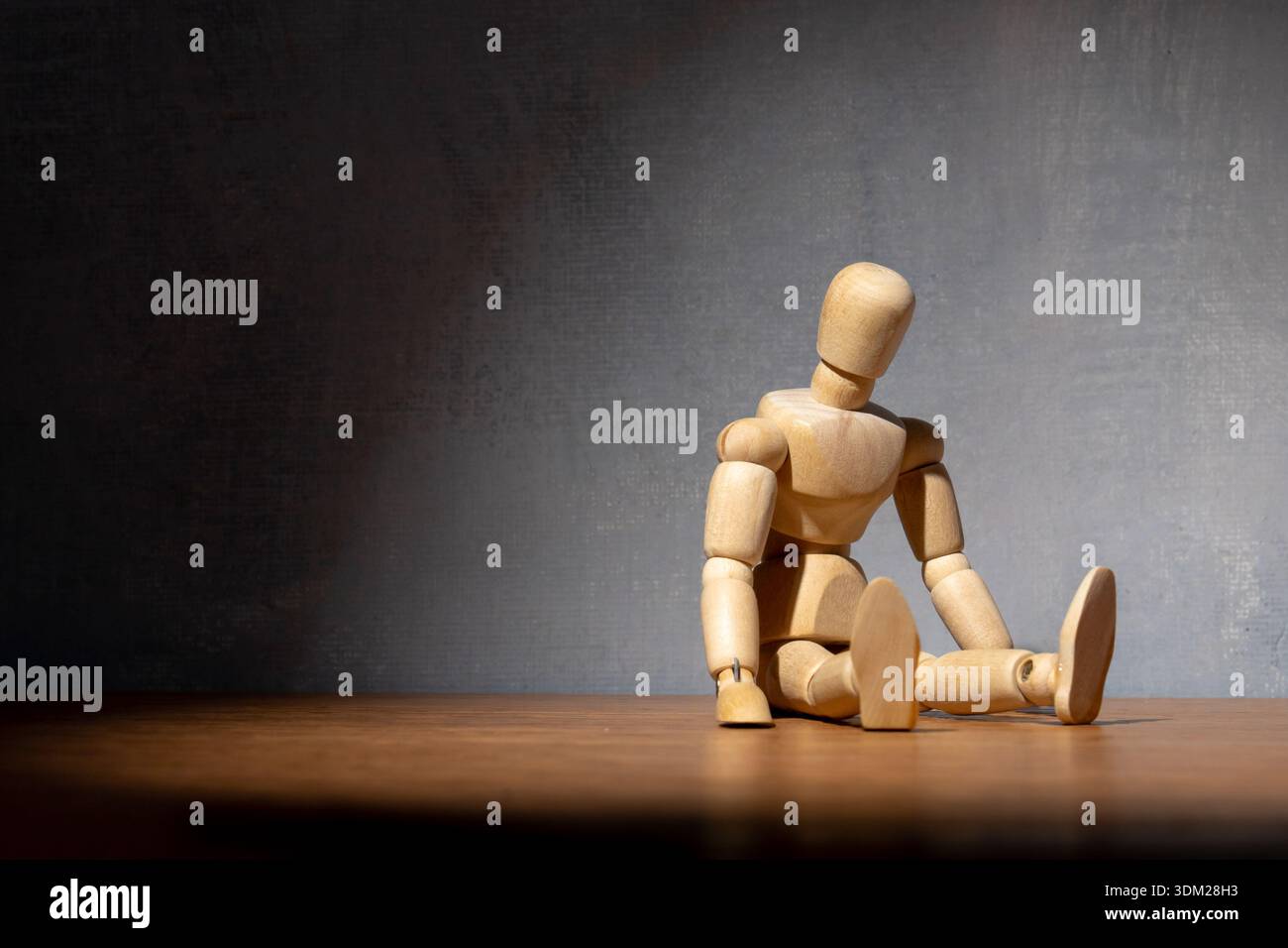 Eine hölzerne Puppe sitzt in einer besiegten Haltung. Depression, Burnout, Einsamkeit, Müdigkeit, psychische Gesundheit kämpft Konzept. Kopierbereich für Text. Stockfoto