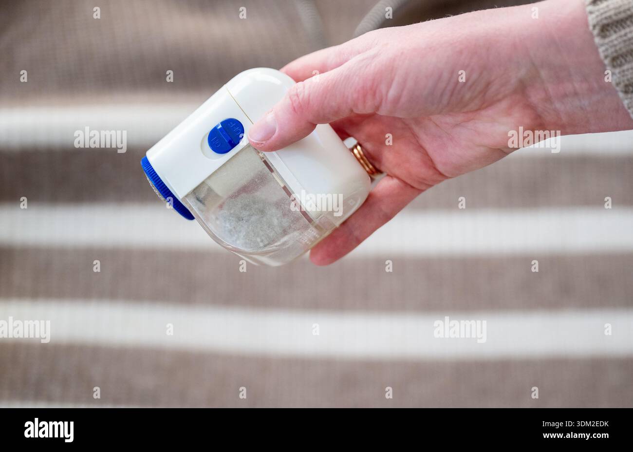 Elektrischer Textilrasierer in weiblicher Hand zum Entfernen von Fusseln aus dem Pullover Stockfoto