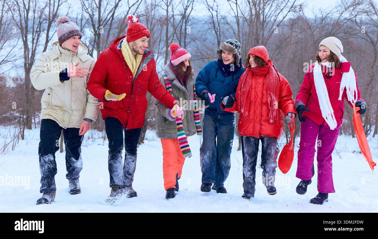 Gruppe von Freunden, die gemeinsam durch den verschneiten Park laufen. Stockfoto