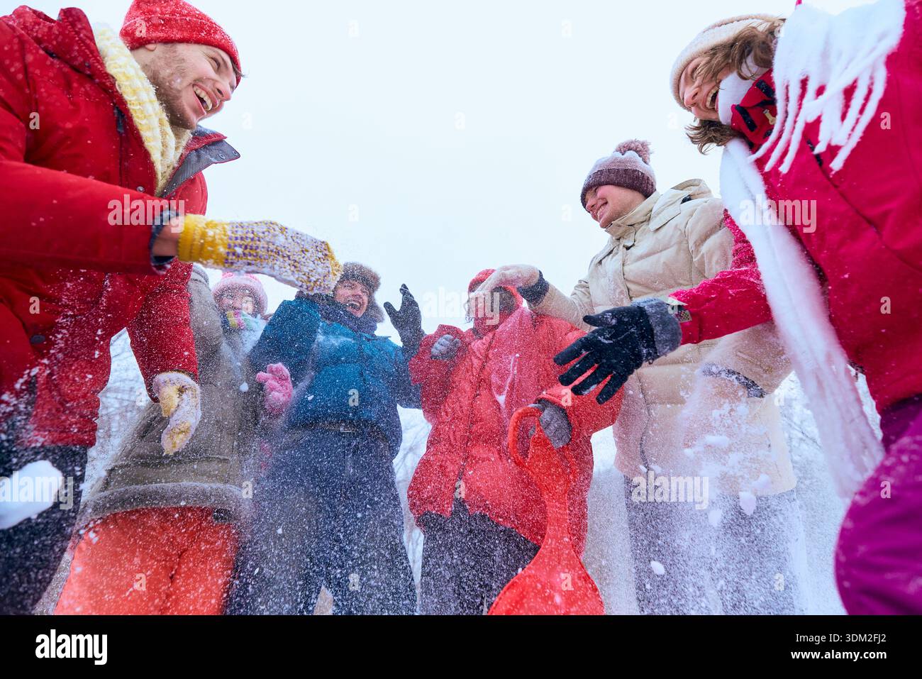Gruppe von Freunden, die Schnee werfen und draußen lachen. Stockfoto