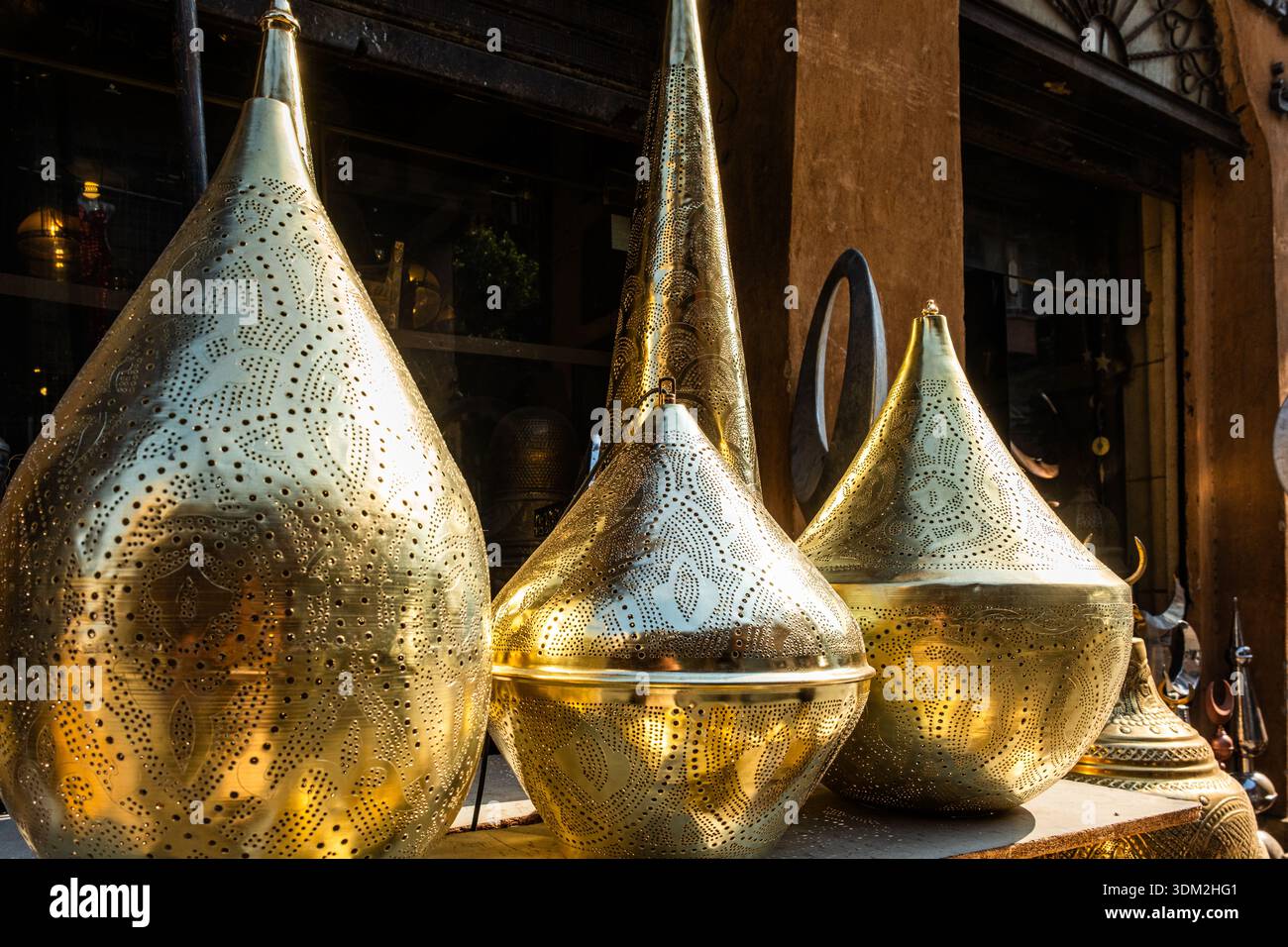 Kunstvoll verzierte Tischleuchten aus Messing, die auf einem Markt ausgestellt werden. Verschiedene Formen und Größen, die traditionelle ägyptische Handwerkskunst widerspiegeln. Ideal für Ramadan-Dekor. Stockfoto
