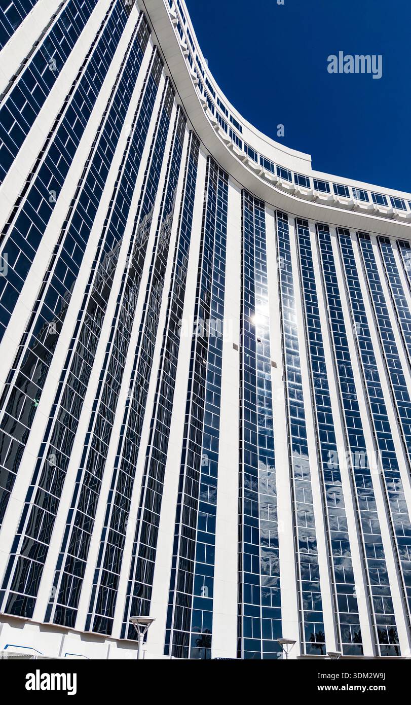 Ikonischer geschwungener, weiß gestreifter Turm des Westgate Las Vegas Resort & Casino vor klarem blauem Himmel, in der Nähe des Las Vegas Convention Center - Smartphone-aufgenommenes Stockfoto